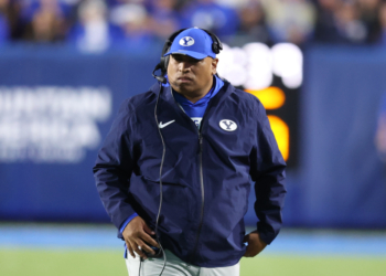 BYU coach Kalani Sitake wearing a headset and blue cap with a 'Y' logo.