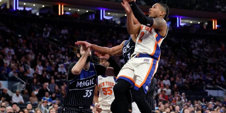 New York Knicks guard Miles McBride (R) puts up a shot past Orlando Magic center Goga Bitadze (L) in the second half at Madison Square Garden in New York, Sunday, December 07, 2025.