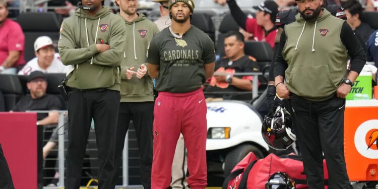 Kyler Murray, injured Arizona Cardinals quarterback, watches from the sideline during an NFL football game.