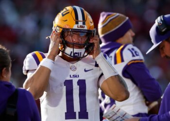 LSU quarterback Michael van Buren Jr. (11) puts on his helmet before a play against Oklahoma during the first half of an NCAA college football game Saturday, Nov. 29, 2025, in Norman, Okla.