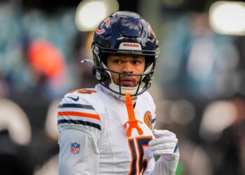 Rome Odunze, a Chicago Bears player, wearing a white jersey with orange and navy stripes on the shoulders, and a navy helmet.