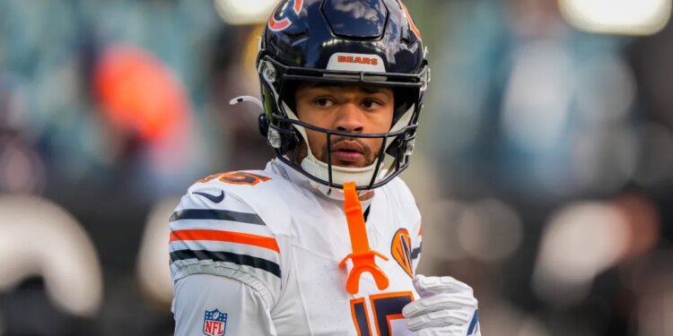 Rome Odunze, a Chicago Bears player, wearing a white jersey with orange and navy stripes on the shoulders, and a navy helmet.