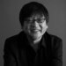 A black-and-white photo of film director Mamoru Hosoda.