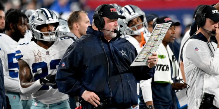 Dallas Cowboys head coach Mike McCarthy on the sideline holding a play chart.