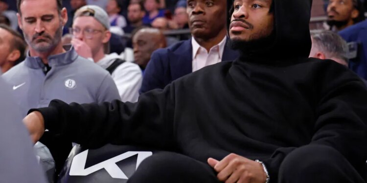 Cam Thomas #24 of the Brooklyn Nets on the bench in plain clothes.