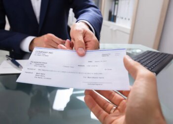 A businessman in a suit handing a check to another person.