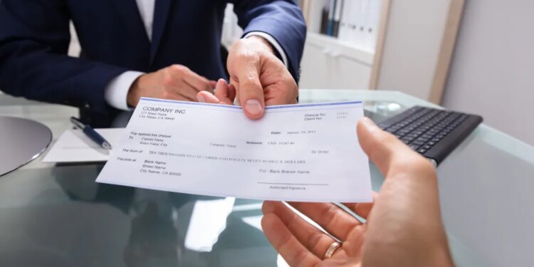 A businessman in a suit handing a check to another person.