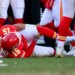 Kansas City Chiefs quarterback Patrick Mahomes clutches his knee after being injured during the second half of a football game.
