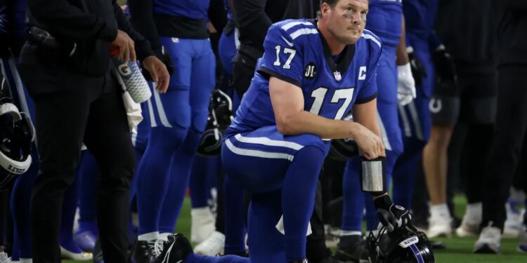 Indianapolis Colts quarterback Philip Rivers (17) on one knee looking on with his helmet in hand.