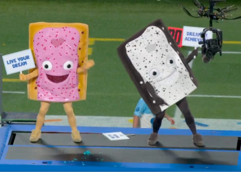 Two people in Pop-Tart mascot costumes on a platform at a football game.