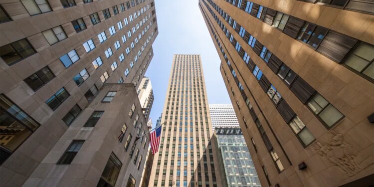 75 Rockefeller Plaza viewed from below, showing the building's exterior and several adjacent skyscrapers.