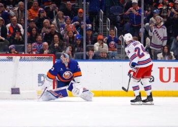 New York Islanders goalie David Rittich deflects the puck from New York Rangers player Carson Soucy.