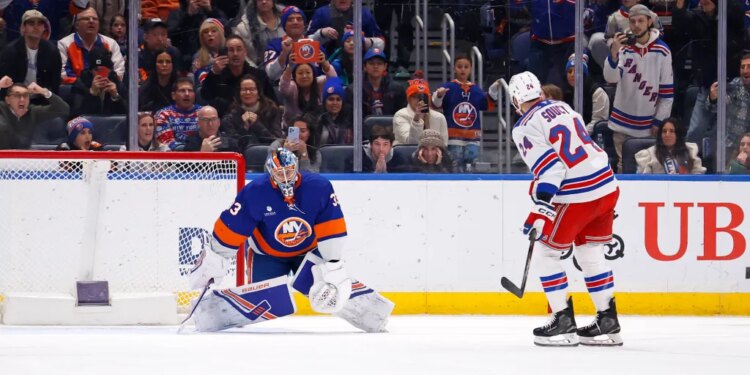 New York Islanders goalie David Rittich deflects the puck from New York Rangers player Carson Soucy.
