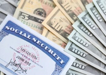 US Social Security card on a pile of US dollar bills.