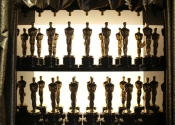 Multiple Oscar statuettes on shelves backstage.