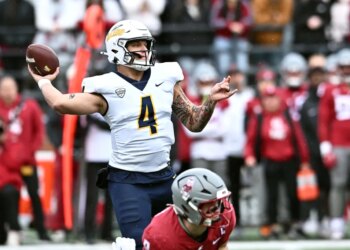 A Toledo player wearing a white helmet and jersey with number 4 preparing to throw a football.