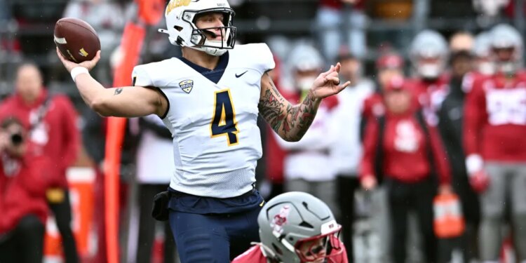 A Toledo player wearing a white helmet and jersey with number 4 preparing to throw a football.