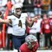 A Toledo player wearing a white helmet and jersey with number 4 preparing to throw a football.