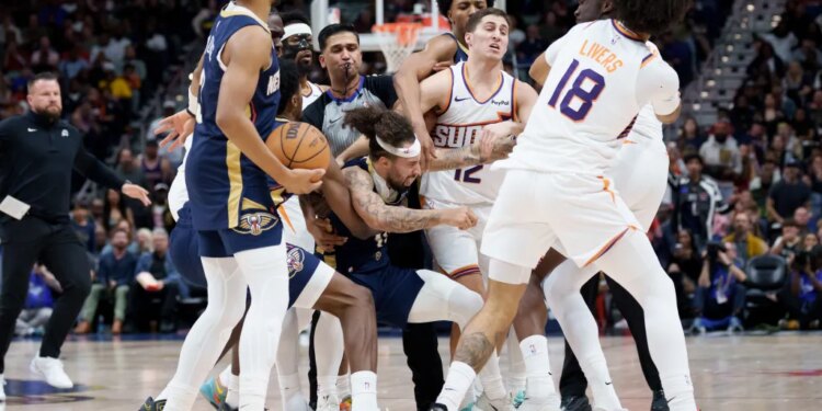 Several basketball players from the Suns and Pelicans engaged in a scrum, with a referee blowing his whistle.