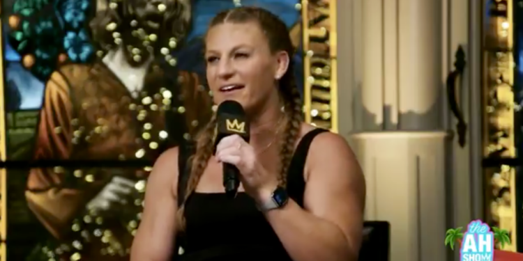 A woman in a black top speaking into a microphone.