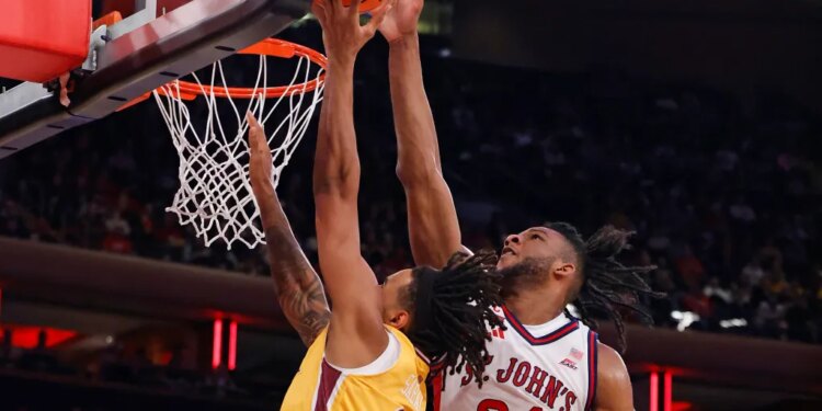 Lamin Sabally of Iona Gaels shooting the ball while Zuby Ejiofor of St. John's Red Storm defends him.