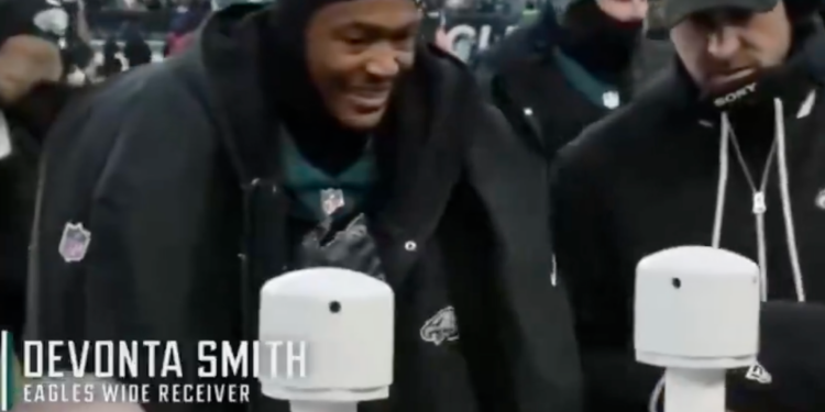 Jalen Hurts smiling on the sideline of a football game.