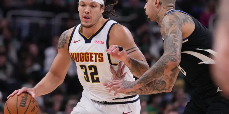 Aaron Gordon of the Denver Nuggets attempting to dribble past Kyle Kuzma of the Milwaukee Bucks during an NBA game.
