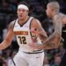 Aaron Gordon of the Denver Nuggets attempting to dribble past Kyle Kuzma of the Milwaukee Bucks during an NBA game.
