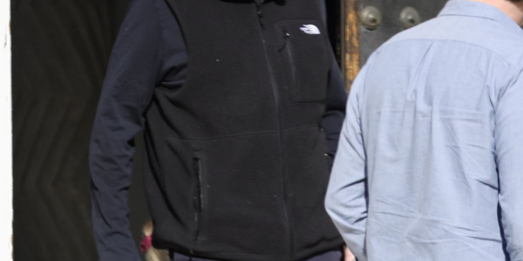 Timothy Busfield in a black vest and dark pants, accompanied by a man in a light blue shirt.