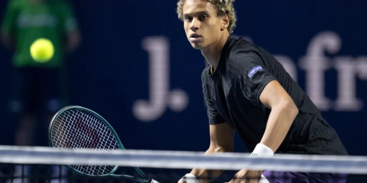 Gabriel Diallo with a tennis racket on court, returning the ball.