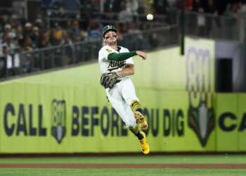Athletics shortstop Jacob Wilson throws a baseball to first base.