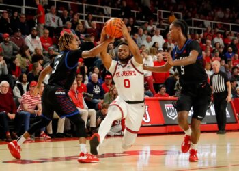 Jamaica, New York 12/07/2022 Posh Alexander #0 of the St. John's Red Storm drives through Jalen Terry #3 of the DePaul Blue Demons and Philmon Gebrewhit #5 of DePaul as he drives to the basket during the first half of an NCAA basketball game at Carnesecca Arena on the St. John's campus on December 7, 2022. (Paul J. Bereswill) DePaul Blue Demons vs St. John's Red Storm