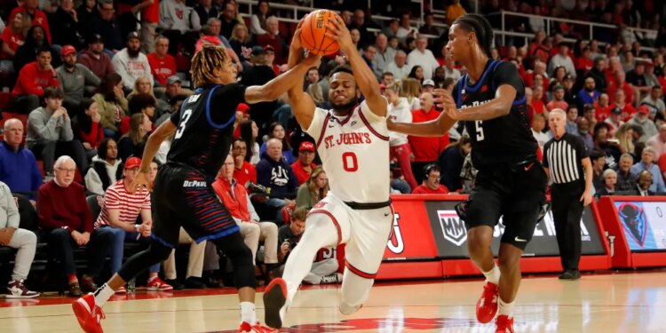 Jamaica, New York 12/07/2022 Posh Alexander #0 of the St. John's Red Storm drives through Jalen Terry #3 of the DePaul Blue Demons and Philmon Gebrewhit #5 of DePaul as he drives to the basket during the first half of an NCAA basketball game at Carnesecca Arena on the St. John's campus on December 7, 2022. (Paul J. Bereswill) DePaul Blue Demons vs St. John's Red Storm