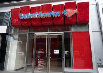 Exterior of a Bank of America branch in New York City with a prominent red sign and logo.