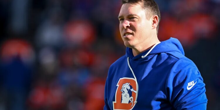 A man in a Denver Broncos hoodie at an NFL game.
