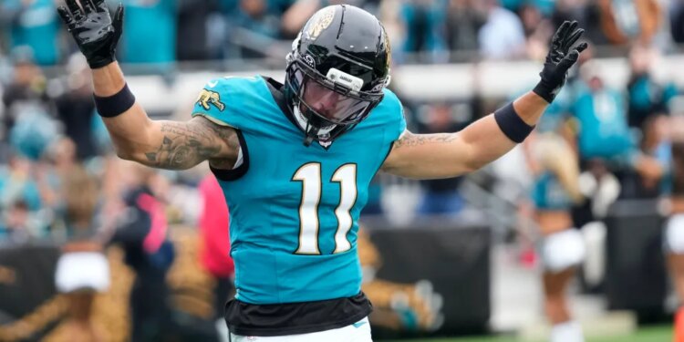 A Jacksonville Jaguars player wearing number 11 raises his arms in celebration.