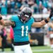 A Jacksonville Jaguars player wearing number 11 raises his arms in celebration.