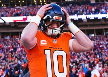 Denver Broncos quarterback Bo Nix wearing an orange jersey with the number 10, putting on his helmet with "5280" written on it.