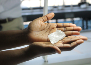 Hands holding a raw diamond.