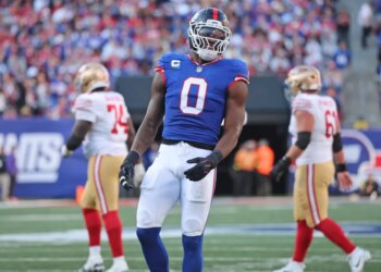 New York Giants player Brian Burns #0, wearing a blue jersey and white pants, on the field during the third quarter.