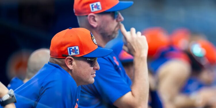 New York Mets manager Carlos Mendoza and pitching coach Jeremy Hefner in orange and blue caps.