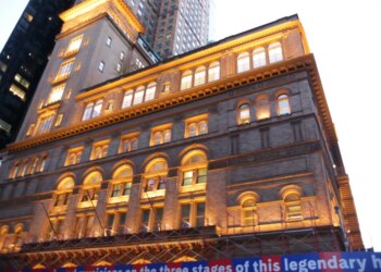 Carnegie Hall building with a blue banner below scaffolding.