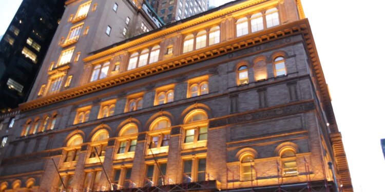 Carnegie Hall building with a blue banner below scaffolding.