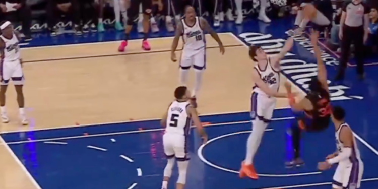 A basketball player in a black and red uniform dunks the ball into a hoop.