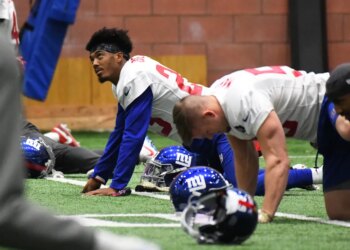 New York Giants defensive back Sam Beal #23 and other players stretch on the ground during practice.