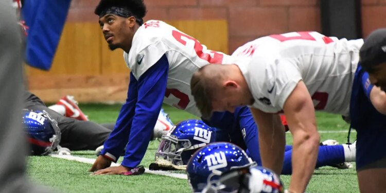 New York Giants defensive back Sam Beal #23 and other players stretch on the ground during practice.
