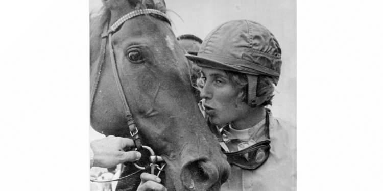 Diane Crump, wearing a jockey helmet, kisses her horse Tou Ritzi, who is bridled.