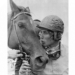 Diane Crump, wearing a jockey helmet, kisses her horse Tou Ritzi, who is bridled.