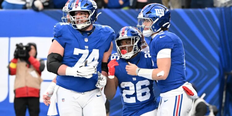 New York Giants running back Devin Singletary (26) celebrates with New York Giants guard Greg van Roten (74) and New York Giants quarterback Jaxson Dart (6) after he runs the ball in for a touchdown during the fourth quarter of the Giants and Dallas Cowboys game in East Rutherford, NJ.