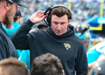 Jacksonville Jaguars offensive coordinator Grant Udinski adjusts his headset on the sideline during a football game.